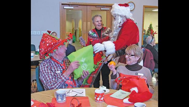 SANTA (DOC GOHMAN) hands out goodie bags to attendees of Thursday’s Young at Heart event. 