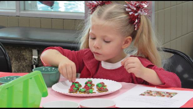 FOUR-YEAR-OLD RILYNN TREPTAU concentrates on creating the perfect masterpiece during Becker Community Center’s Cooking with Mrs. Claus event last Saturday. (Photo by Penny Leuthard)