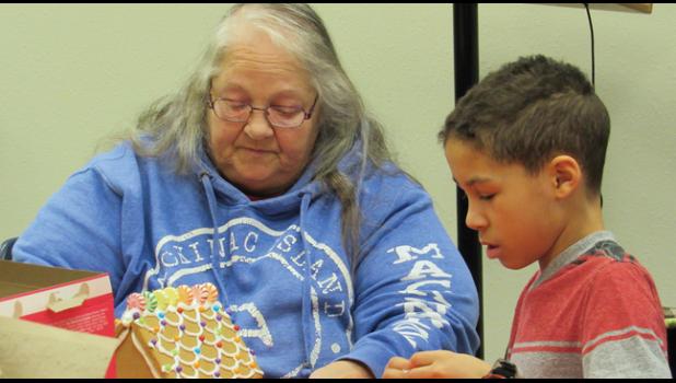Kathy Arneson and her grandson, Rylee Spurling decorate a gingerbread house at TCA’s live nativity event Sunday evening. (Photo by Penny Leuthard)