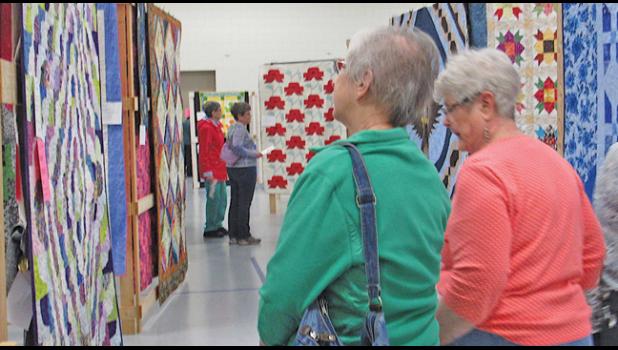 ATTENDEES OF THE BECKER GUILD’S QUILT SHOW admire some of the 114 creations on display at the Becker Community Center Saturday. (Photo by Penny Leuthard)