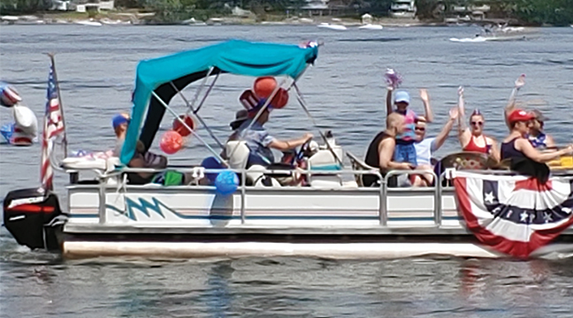 RED, WHITE AND BLUE, adorned the boats as they cruised by for the annual fourth of July parade on Big Lake.  