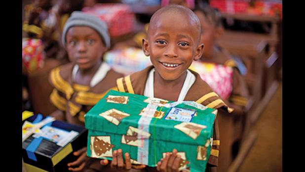 THIS CHILD from Liberia was all smiles last year as he held a shoebox containing many items including toys, hygiene items and school supplies. This is the kind of joy OCC brings to children all across the planet. (Photo from Samaritan’s Purse website).