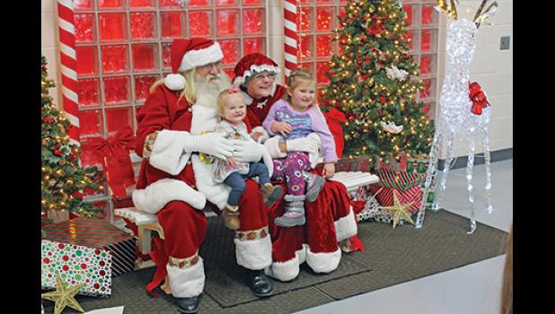 LITTLE ONE-YEAR-OLD EMMA (on Santa’s lap) and her sister Lily (3) were all smiles as they posed for photos with Mr. and Mrs. Santa Claus at the Breakfast with Santa event Saturday at the BCC. Emma and Lily’s mom, Julie Sura of Becker, was nearby snapping photos of her own. (Photos by Bill Morgan).